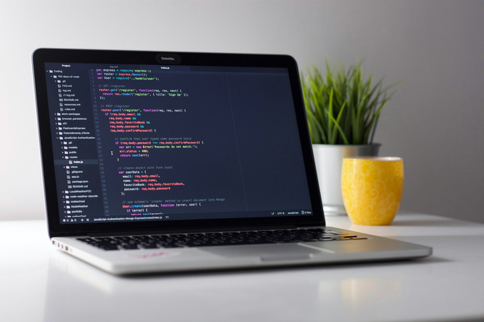 Person coding on a laptop in a workspace