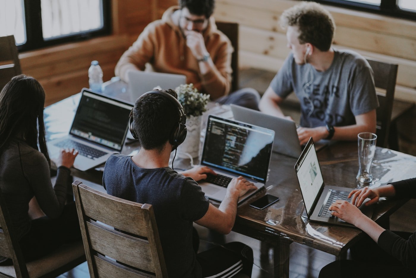 Team collaborating around laptops in a modern office discussing AI coding tools